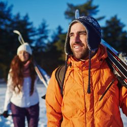 Couple of sporty travelers with skis spending winter vacation at ski-resort